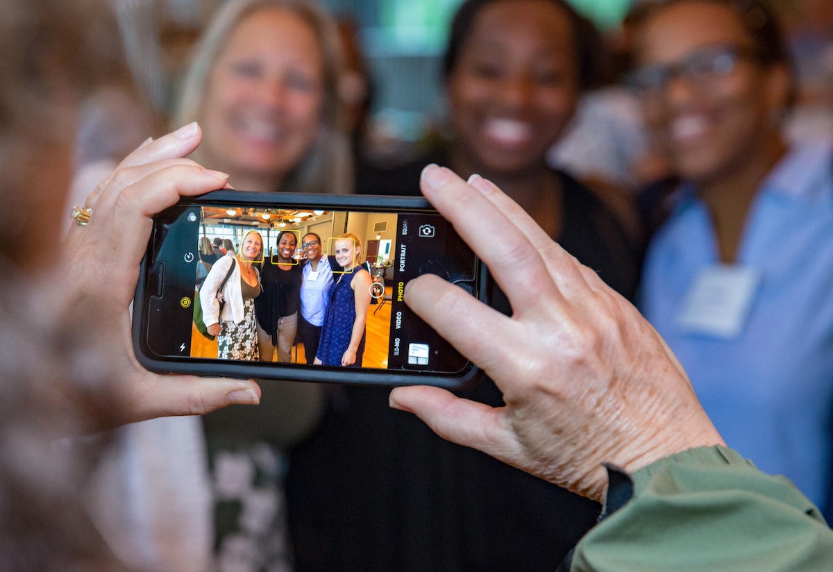 Someone taking a photo of four people with a mobile phone