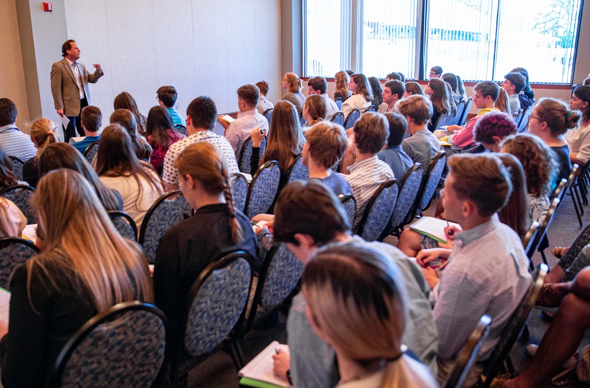 Someone standing in front of a large audience speaking